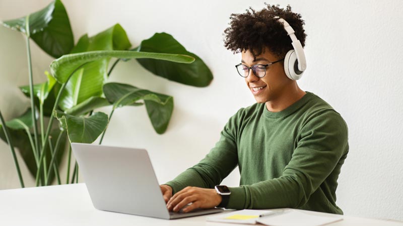 jovem de phones a trabalhar no portátil